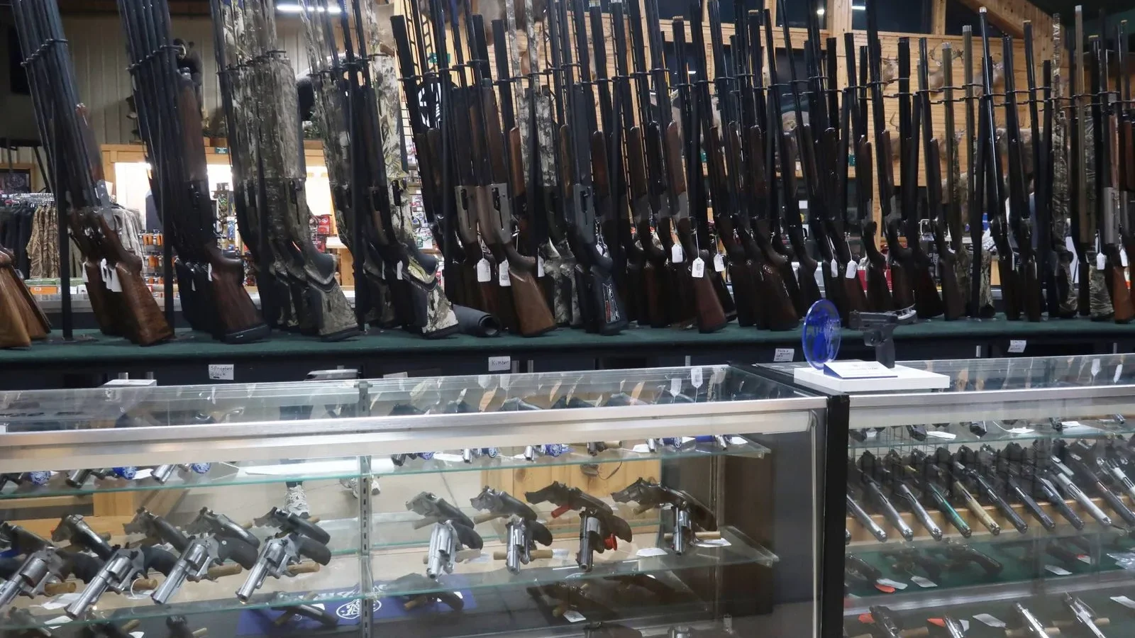 Gun shop display with rifles on wall rack and handguns in glass cases at Midwestern Shooter's Supply.