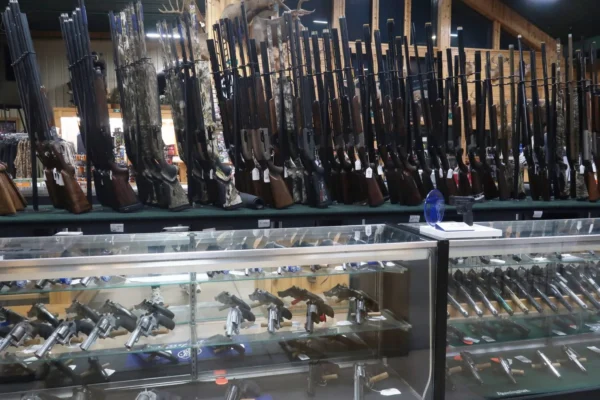 Gun shop display with rifles on wall rack and handguns in glass cases at Midwestern Shooter's Supply.